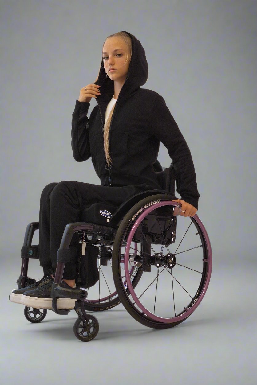 Girl in a wheelchair dressed in Vilber's woman's jersey wheelchair adaptive pants and black jacket