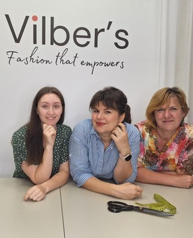 Drie teamleden van Vilber's bij de merkwand